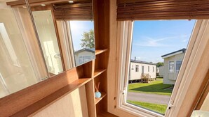 Une petite salle de bain comprenant des toilettes, un lavabo et une fenêtre donnant sur un quartier résidentiel.