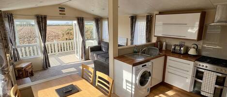 A compact kitchen with a washing machine, a stove, and a dining area with a table and chairs.