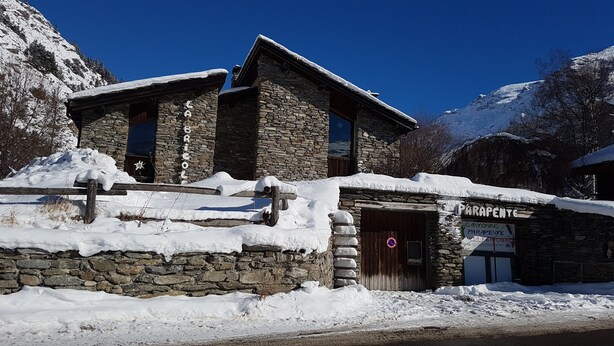 A stone building with a sign reading 'BRICOLE' and another sign for 'PARAPENTE'.