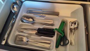 A drawer with various utensils including spoons, forks, knives, and scissors.