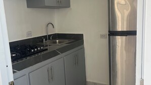 Una cocina con armarios grises, un refrigerador de acero inoxidable, una ventana y un piso con baldosas.