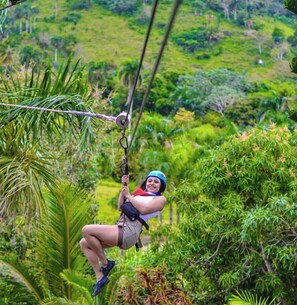 A person zip-lining through a lush, green forest. - Ruka Hotel  (Punta Cana)