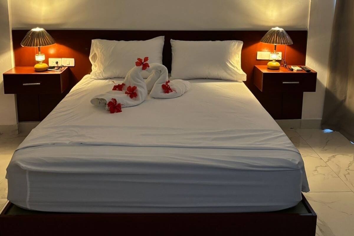 A hotel room with a large bed, two bedside tables with lamps, and a marble floor.