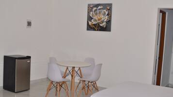Quarto com mesa de jantar, cadeiras, geladeira e uma porta.