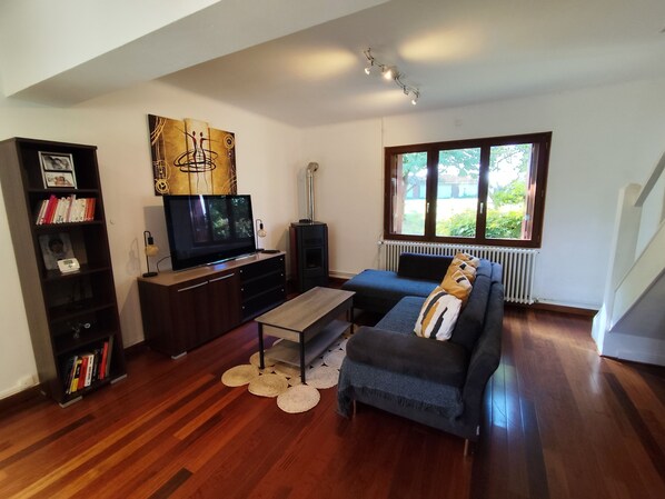 Ein modernes Wohnzimmer mit Flachbildfernseher, einer Couch, einem Couchtisch und einem Bücherregal.