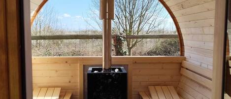 A sauna with wooden benches and a central heating unit.