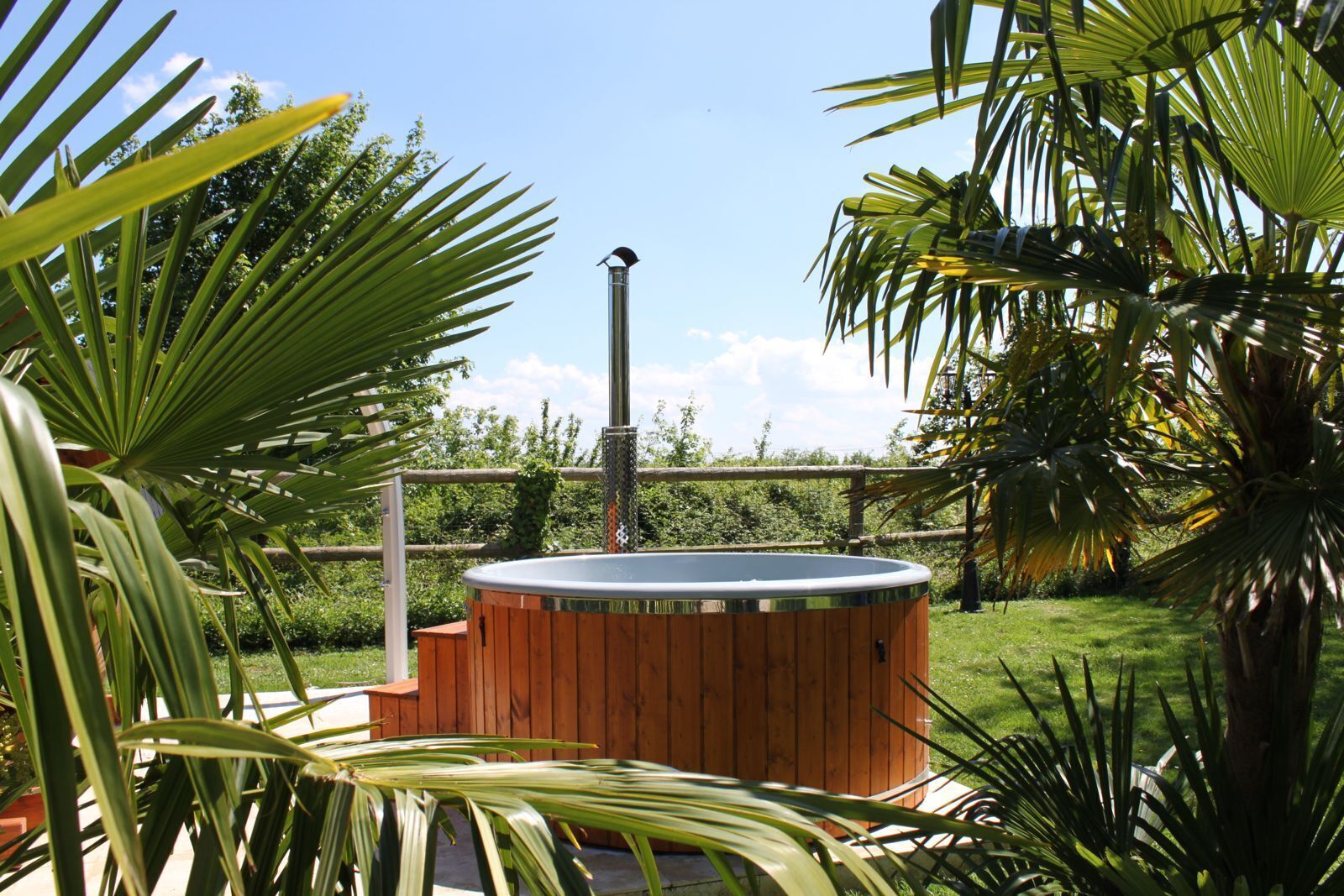 A hot tub surrounded by lush greenery and a wooden fence.
