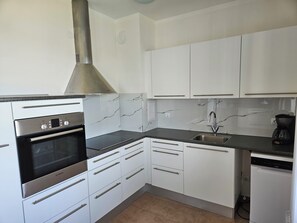 A modern kitchen with white cabinets, a Bosch oven, a stainless steel range hood, a sink, and a dishwasher. - Vacation apartment Byala Black Sea (Byala)