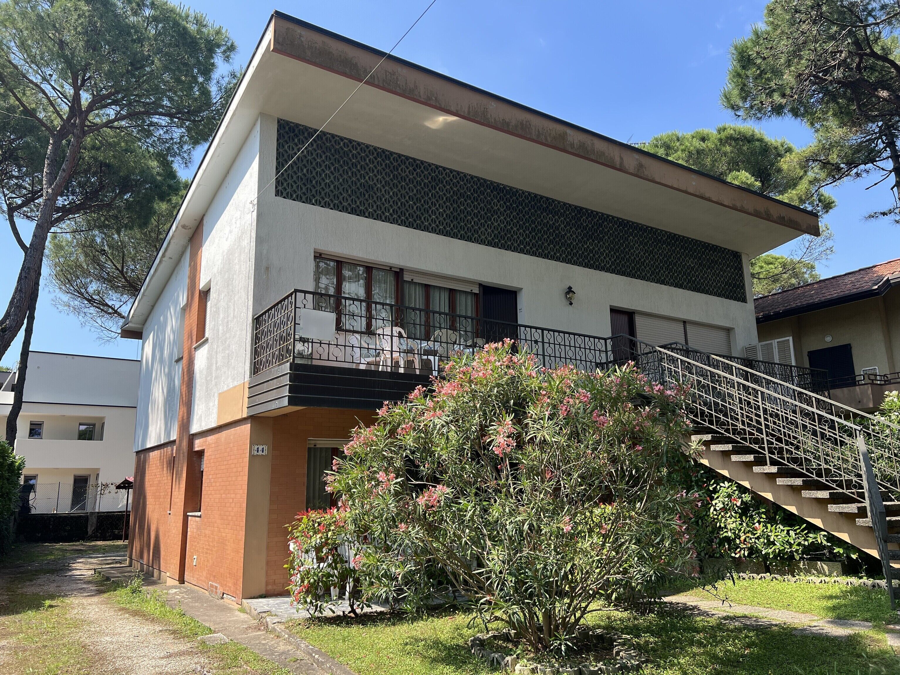 A two-story building with a balcony, a staircase, and a garden area.