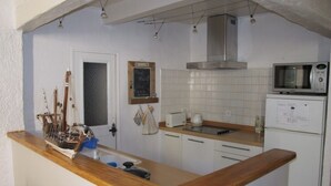 A kitchen with white cabinets, a wooden countertop, a microwave, a coffee maker, and a chalkboard on the wall. - Charming apartment at the foot of the Luberon ochres (Rustrel)