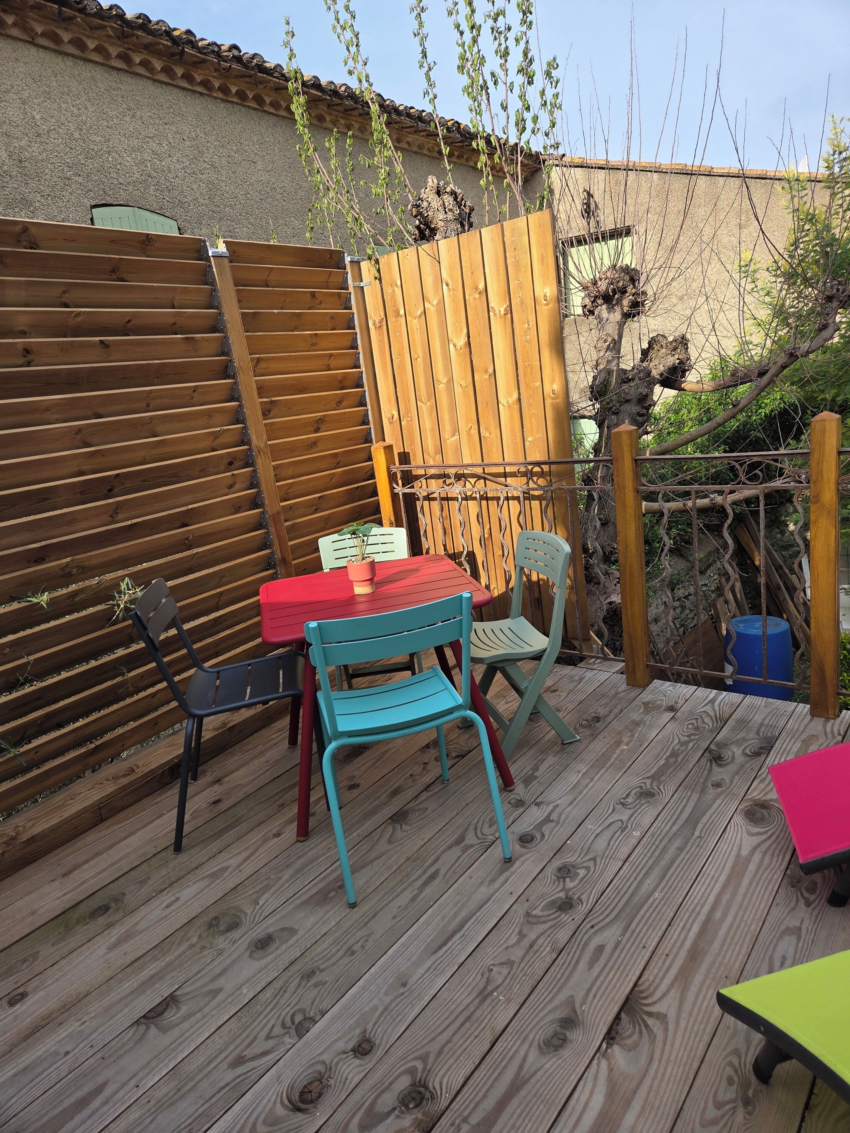 Une terrasse en bois avec une table et des chaises, une clôture en bois et un arbre.