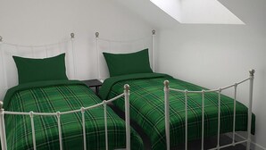 Un dormitorio con dos camas, un tragaluz y un ventilador de techo.