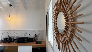 Une cuisine au design moderne, agrémentée d’une œuvre d’art murale en bois, d’un luminaire suspendu et d’un plan de travail sur lequel sont disposés divers appareils électroménagers.
