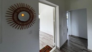 Un couloir agrémenté d’une œuvre d’art murale contemporaine, une porte donnant sur une pièce et un plancher en bois.