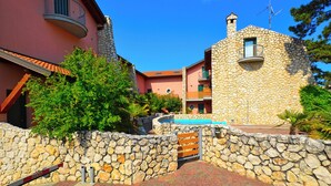 A stone building with a balcony, a pool, and a stone wall. - Villa With Pool in Lignano (Lignano Sabbiadoro)