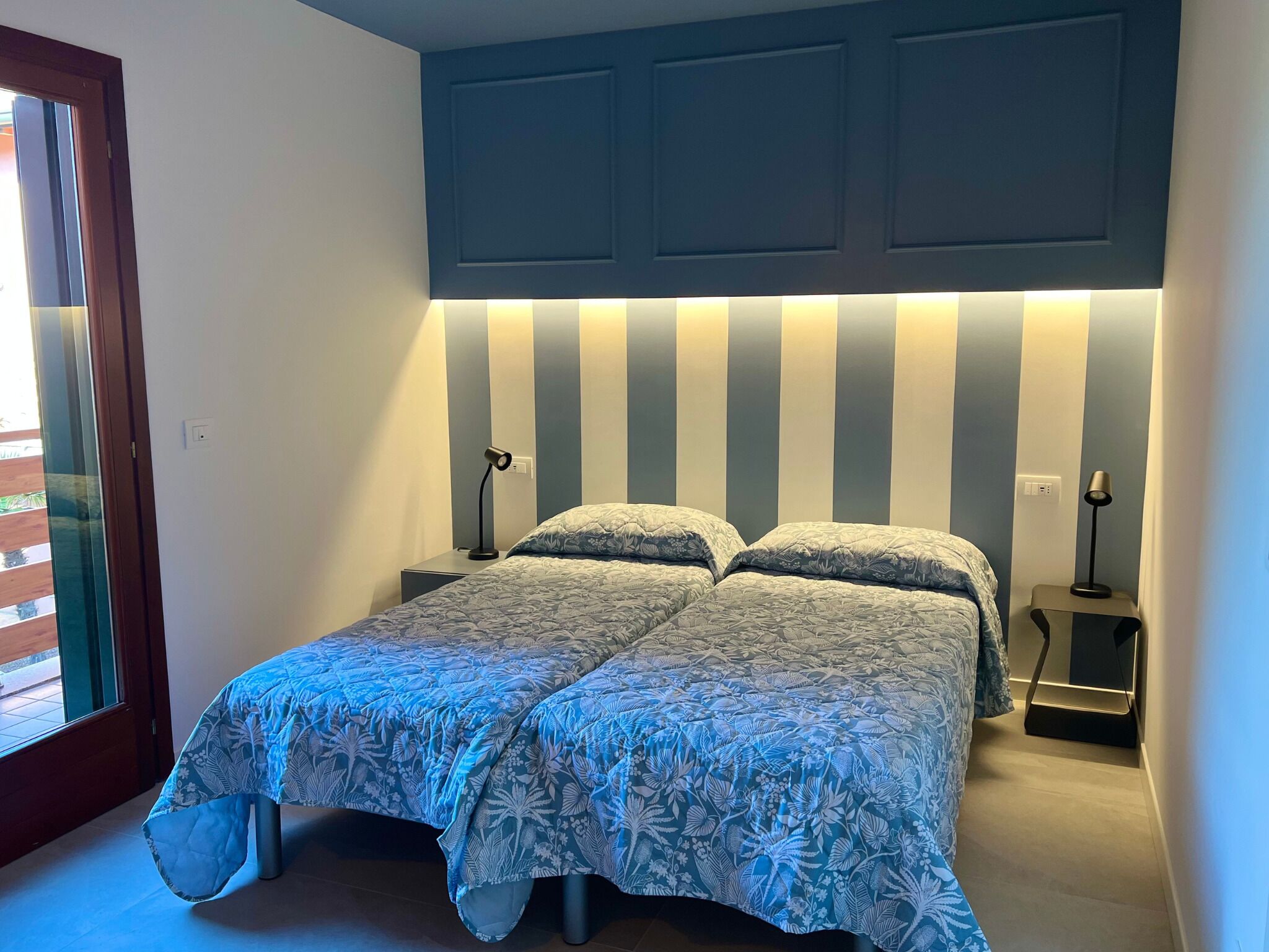 A bedroom with a bed, two bedside tables, and a window.