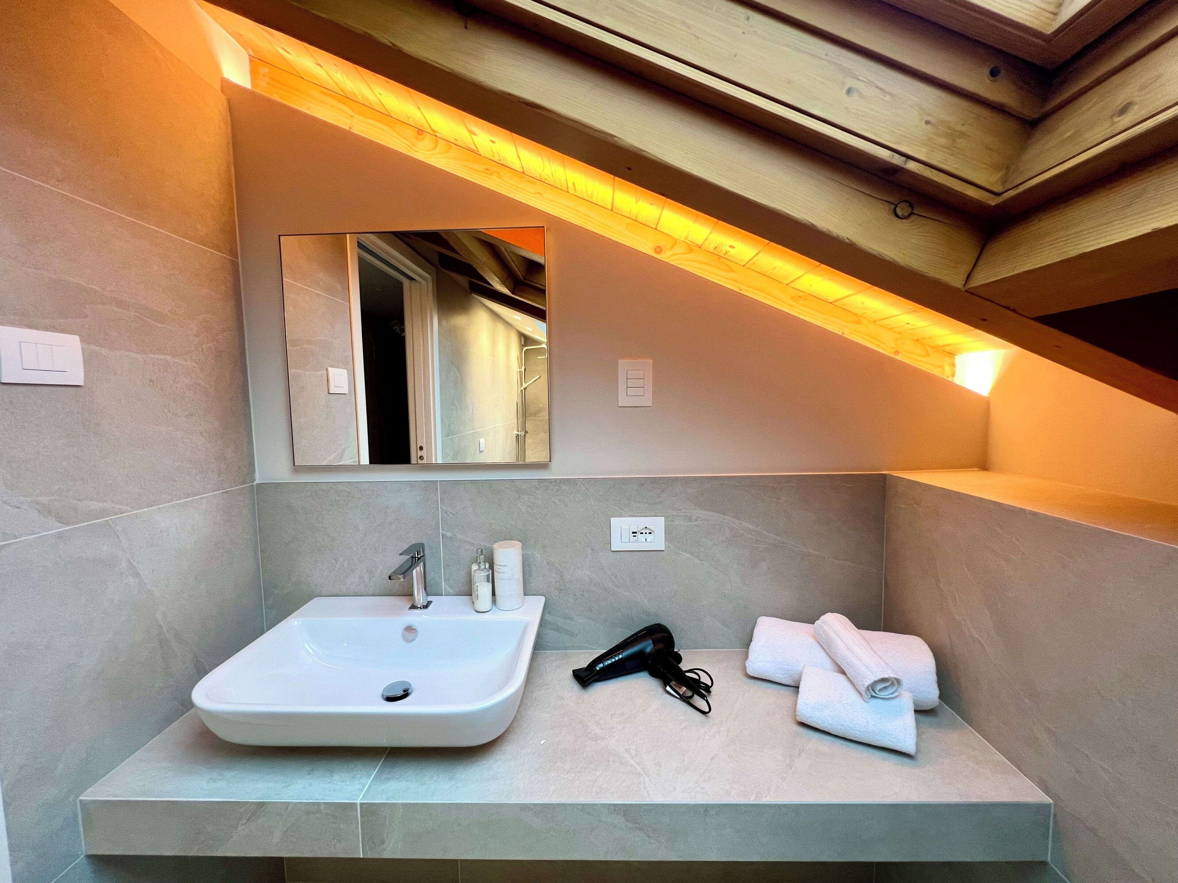 Ein Badezimmer mit Waschbecken, Spiegel, Handtuchhalter und einem Föhn.