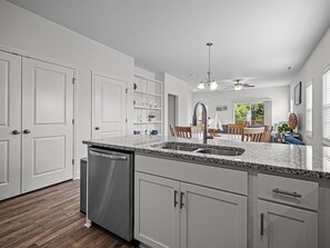 A modern kitchen with granite countertops, stainless steel appliances, and a dining area with wooden chairs. - Boater's Cove, 3BR/2BA, Neighborhood Boat Ramp (Cedar Point)
