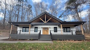 Une maison à deux étages avec un porche à l’avant, une porte en bois et un garage.