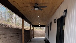 Un espace extérieur abrité, doté d’un ventilateur de plafond, d’un sol en béton et d’un mur en briques.