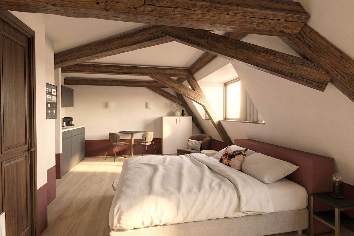 Un dormitorio con techo inclinado, una cama, un escritorio y una silla.