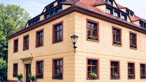 Un bâtiment jaune avec un toit rouge, de nombreuses fenêtres et une rue pavée.