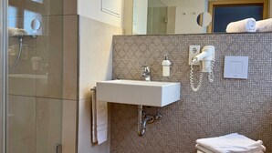 Une salle de bain moderne avec une douche Ă parois de verre, un lavabo blanc, des toilettes et un miroir.