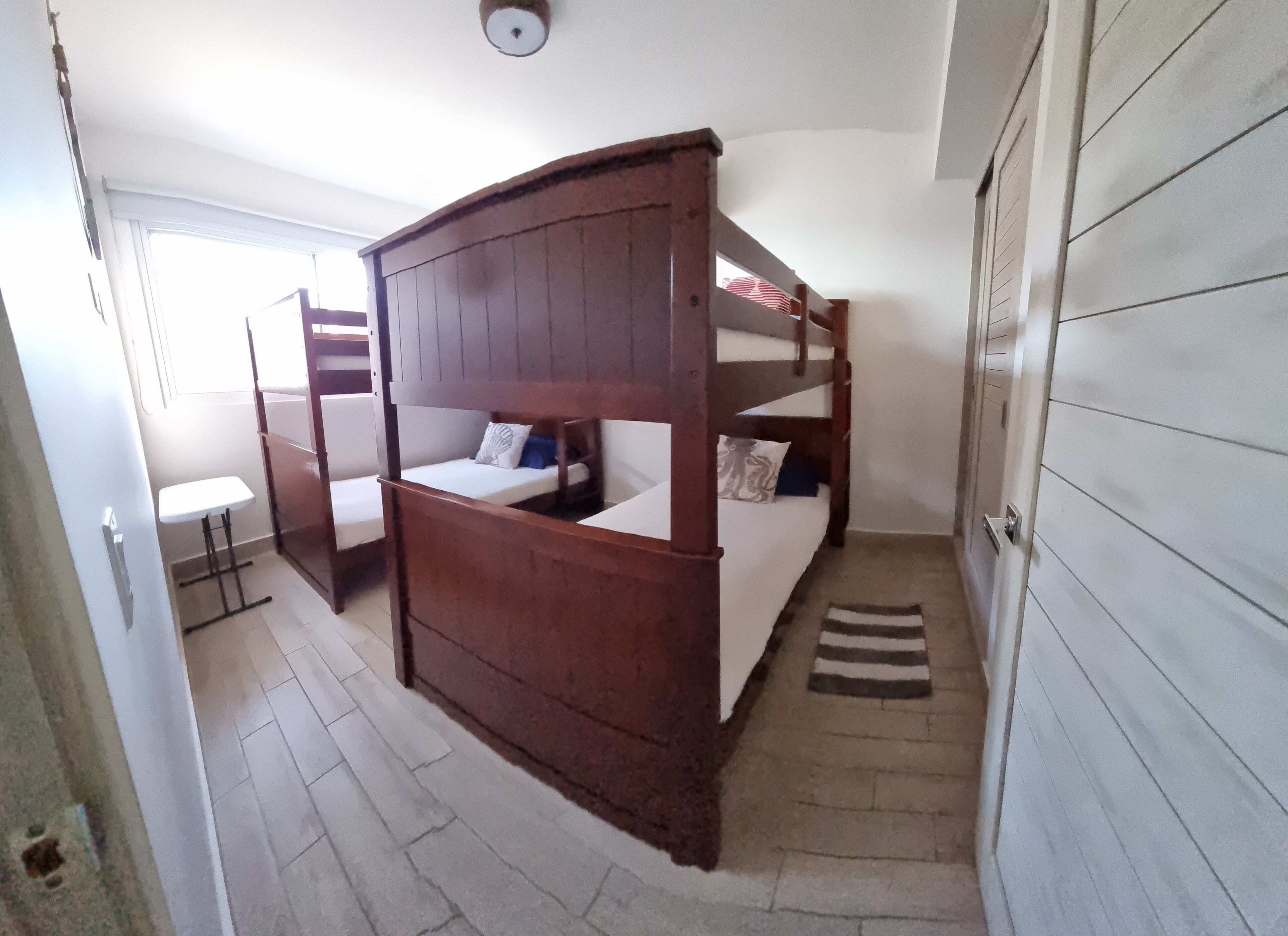 A bunk bed room with a small table and a door.