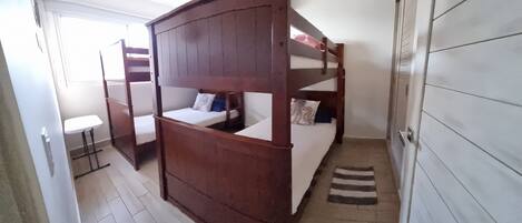 A bunk bed room with a small table and a door.