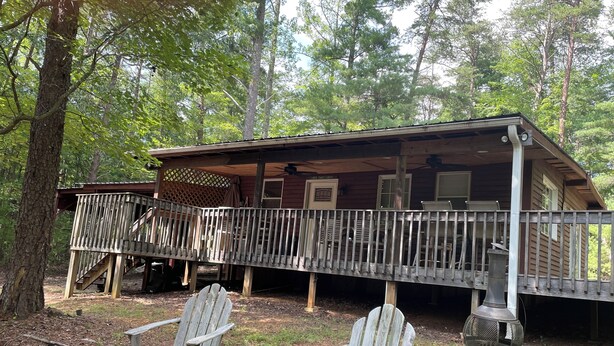 A cabin with a deck, outdoor seating, and a grill. - Soothing 2-bedroom cabin with AC in charming Bassett (Bassett)