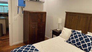 A bedroom with a bed, a wardrobe, a bedside lamp, and an air conditioning unit. - Soothing 2-bedroom cabin with AC in charming Bassett (Bassett)
