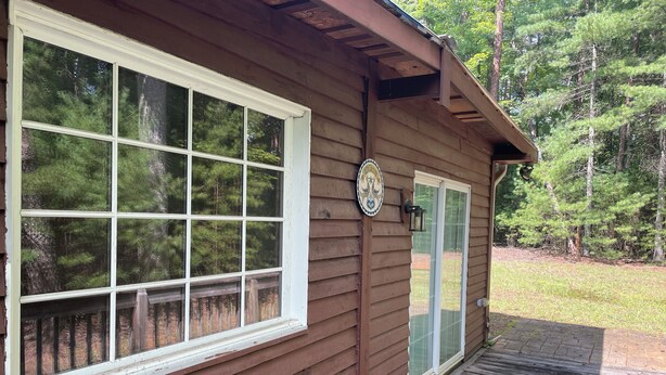 Een houten chalet met een groot raam, een deur met een ruitpaneel en een klein terras.