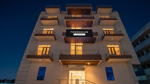 A multi-story building with a sign reading 'TOWNHOUSE' and 'Company-Serviced.'