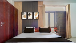 A hotel room with a bed, a wardrobe, a wall-mounted artwork, and a window with curtains.