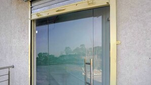 A glass door with a metal handle, a metal railing to the left, and a textured wall.