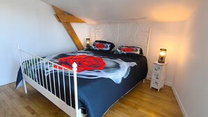 Une chambre à coucher avec un lit, une table de chevet, une lampe et une poutre en bois au plafond.