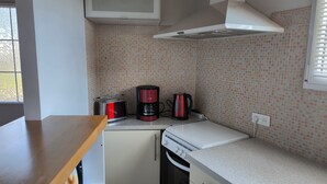 Une cuisine compacte équipée d’un grille-pain, d’une machine à café et d’un four.