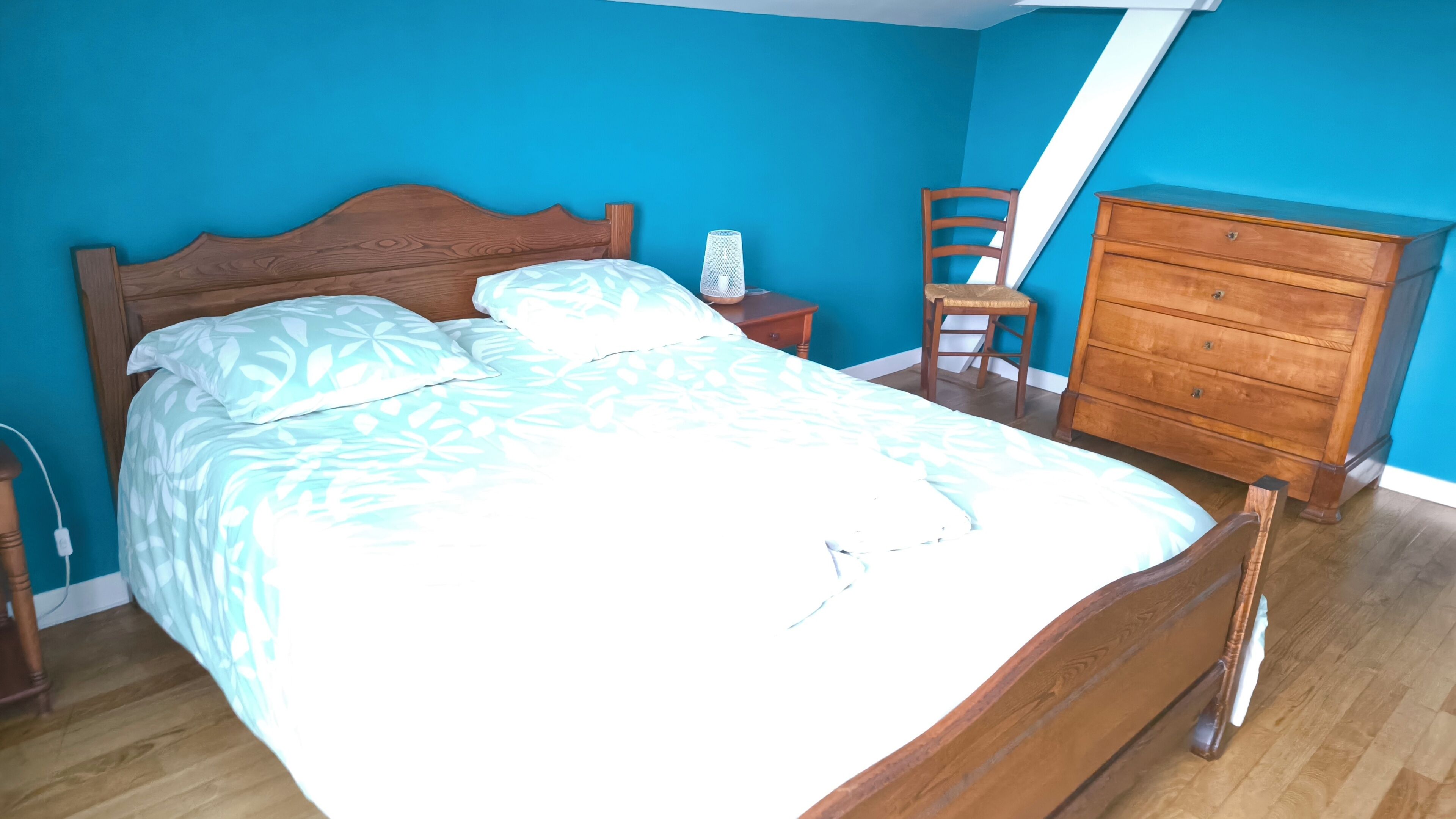 A bedroom with a wooden bed, a nightstand, a dresser, and a chair.