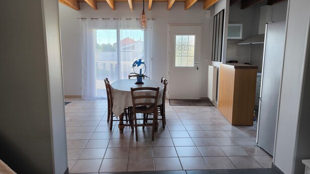 Un coin repas avec une table et des chaises, une cuisine équipée et une vue par la fenêtre.
