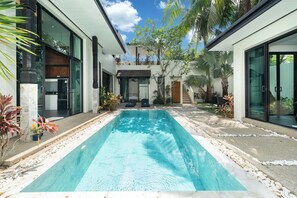 Una casa moderna con piscina, ventanas amplias y jardín.