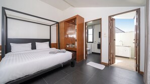 A modern bedroom with a large bed, a wooden wardrobe, a bathroom with a toilet and sink, and a view of the outside. - Wings 25 Laguna (Phuket)