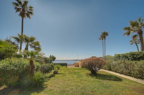 A well-maintained garden with palm trees, a pathway, and a view of the sea. - 6-bedroom villa, Croisette seafront (Cannes)