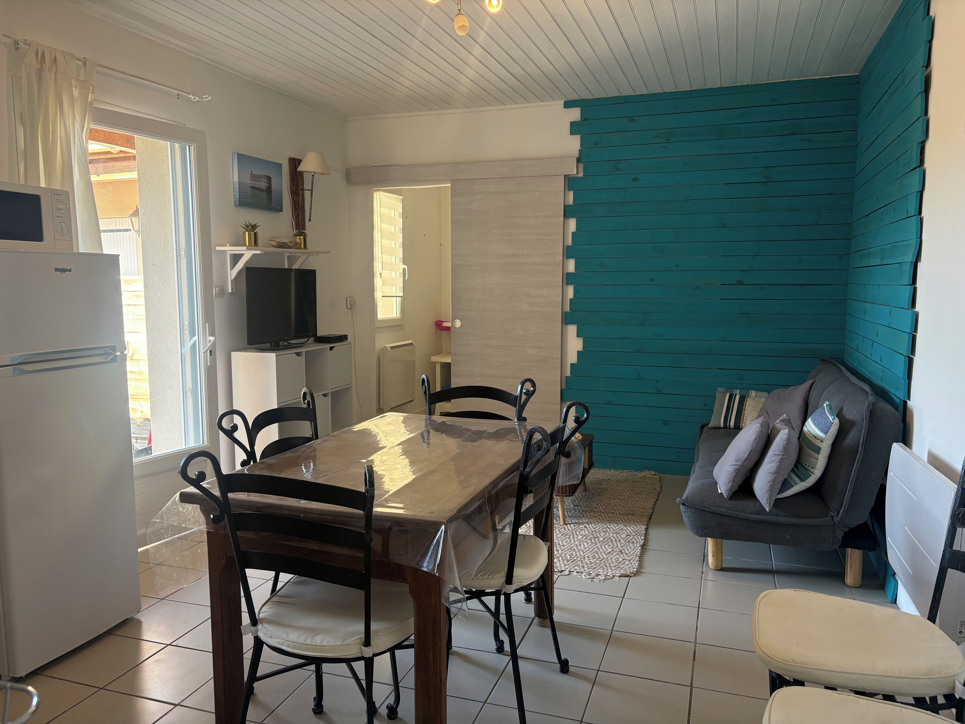 A compact living space with a dining table, chairs, a sofa, and a television.