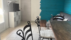 A dining area with a wooden table, black metal chairs, a television, and a white cabinet. - House near the beach (Saint-Georges-d'Oléron)