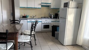 A kitchen with white cabinets, a stove, a microwave, and a refrigerator. - House near the beach (Saint-Georges-d'Oléron)