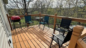 Una terraza de madera con mobiliario exterior y una parrilla.