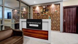 A reception area with a sign reading 'TOWNHOUSE Company Serviced,' a clock, and a door labeled '201.'