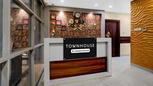 A reception desk with a sign reading 'TOWNHOUSE Company-Serviced,' a clock, and framed pictures on the wall.