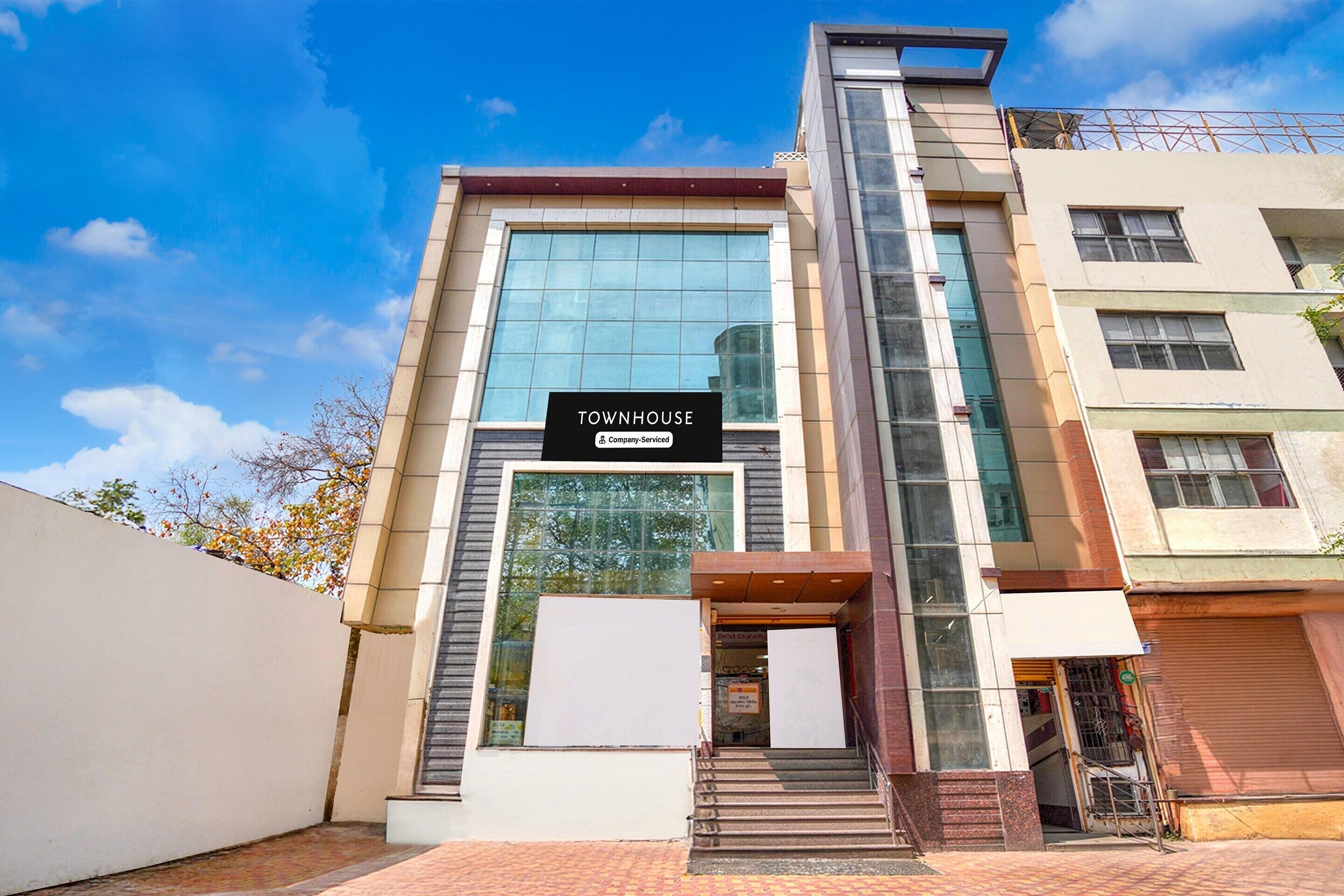 A modern townhouse with a prominent 'Townhouse & Company-Serviced' sign, large windows, and a brick-paved entrance.