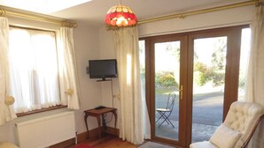 A room with a sofa, a red rug, a television, and a chair. - Fantastic bungalow in quiet rural setting close to Enniscorthy town. Sleeps 6. (Enniscorthy)